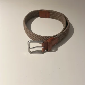 Beige flätat bälte från Jack & Jones - Snyggt beige flätat bälte från Jack & Jones med detaljer i brunt skinn och silverspänne. Bältet har en bred, vävd design som ger en cool och avslappnad look. Perfekt accessoar för att lyfta din outfit med en stilren touch. Pris ej hugget i sten!! Mvh