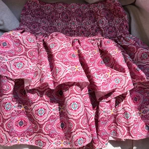Rosa mönstrad kortkjol Meet x Tiger - Supersöt kortkjol från Meet x Tiger i rosa med färgglatt paisleyinspirerat mönster. Kjolen har smockad midja som sitter bekvämt och har inbyggda shorts under om de skulle vara vindigt💕 Kan posta samma dag