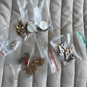 Mixade smyckesberlocker i guld och färg - Stort paket med smyckesberlocker i olika former och färger, bland annat bin, körsbär, stjärnor och zodiak-symboler. De flesta är i guldfärgad metall, vissa med inslag av svart, vitt, rött och grönt. Perfekt för att skapa egna halsband, armband eller örhängen.