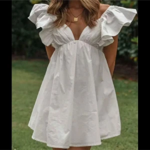 Vit kortklänning med volangärmar - Supersöt vit kortklänning med djup v-ringning och stora volangärmar. 🌸💗