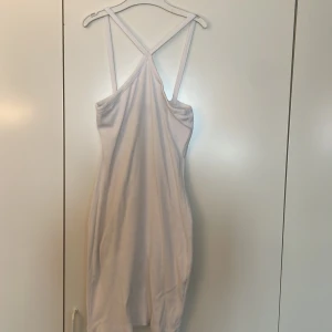 Vit ribbad kortklänning från 157 - Säljer en vit ribbad klänning från 157 i storlek XS. Klänningen har smala axelband som korsas i ryggen och en figurnära passform. Perfekt för dig som gillar det enkelt!