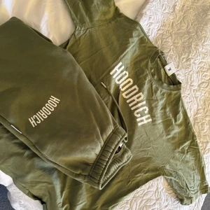 Olivgrön Hoodrich t-shirt XS - Snygg olivgrön t-shirt från Hoodrich i storlek XS. T-shirten har klassisk rund hals och korta ärmar, med Hoodrich-loggan tryckt i vitt framtill. Skön och mjuk bomull som passar perfekt till streetwear-stilen. Och så även ett par matchande byxor till, kommer att sälja dom som ett sett då jag vill bli av med dom så snabbt som möjligt, byxorna är i strl XS men känns som S. Som NYA