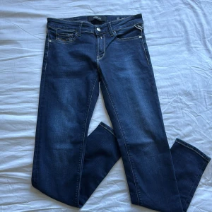 Mörkblå Replay jeans, W27 L28 - Snygga mörkblå jeans från Replay med klassisk femficksdesign och kontrastsömmar. Modellen har raka ben och normal midja. Materialet är mjukt jeans-tyg som sitter skönt hela dagen. Perfekta till sneakers eller boots.