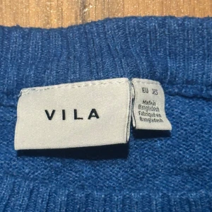 Blå stickad tröja från VILA - Snygg blå stickad tröja från VILA i storlek XS. Tröjan har rund halsringning och långa ärmar, perfekt för att hålla dig varm under kyliga dagar. Enkel och stilren design som funkar till jeans eller kjol. Mjuk och skön kvalitet.