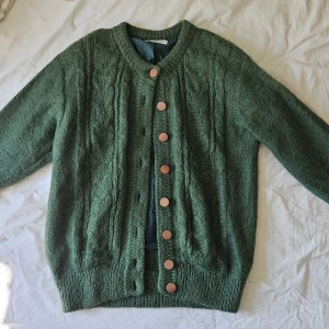 Grön stickad kofta från Racommoder - En jättemysig och varm kofta med knappar. Den har ett silkeslent innerfoder som inte gör den stickig. Mohairull.  Storlek L. Passar även S/M.  Köpt secondhand i Köpenhamn.  Jätte bra skick förutom en söm som har gått upp, se bild. Påverkar inget.