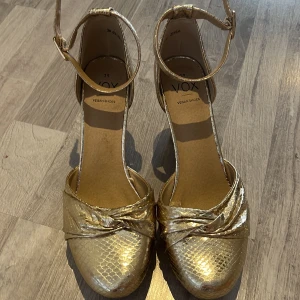 Guldiga pumps med ankelrem från Vox - Säljer ett par guldiga klackar i storlek 39, klacken är ungefär 9 cm och har bara använt två gånger 💕
