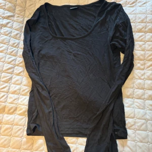 Svart långärmad tröja Gina Tricot - En enkel svart långärmad tröja från Gina Tricot i storlek M. Tröjan har en rundad, lite djupare halsringning och är gjord i mjuk bomull. Perfekt att styla med jeans eller kjol för en clean och chill look.