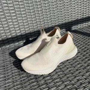 Nike Epic phantom React Flyknit vita sneakers - Nike Epic React Flyknit sneakers i cremefärg. Skorna har en stickad ovandel i flyknit-material som ger en tight och flexibel passform. Sulan är tjock och responsiv med React-dämpning för extra komfort. Slip-on-modell med dragflikar både fram och bak för enkel påtagning. Sneakers löparskor från Nike modell Epic Phantom React Flyknit. Cremefärgade i storlek 38. Testat vid 1 tillfälle. Jag har massor av artiklar till salu! 