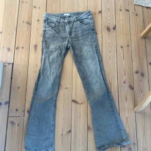 Grå bootcut jeans från Gina Tricot 158 - Säljer ett par grå jeans från Gina Tricot i storlek 158. Jeansen har bootcut-modell med utsvängda ben och klassisk femficksdesign. Materialet är denim och färgen är snyggt tvättad grå, perfekt till sneakers eller boots.