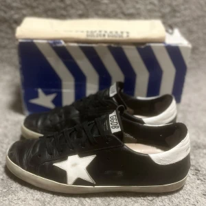 Golden Goose Superstar - Hej, Säljer nu mina otroligt snygga Golden Goose sneakers i en eftertraktad färg och model. Storlek: EU 43 / UK 9 Skick: 7/10, bra skick över lag, förutom några få skavanker samt att jag tidigare lagat en liten slitning vid hälen på skon med hjälp av självhäftande lagningslappar. Nypris: runt 5000kr.  Hör av er för mer bilder och övrig information! Mvh, Elton