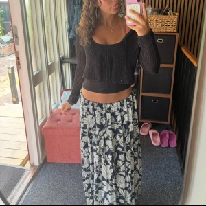 Blommig långkjol  - Superskön långkjol med vitt blommönster på mörkblå botten. Kjolen har en avslappnad passform. perfekt för varma dagar. Elastisk midja för extra komfort och flowig känsla.