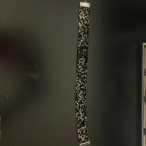 Svart glittrigt choker-halsband - Snyggt svart choker-halsband med glittriga detaljer och silverfärgade metalldelar. Halsbandet har en bred form och justerbar kedja för perfekt passform. Perfekt för att ge din outfit extra edge och glam.