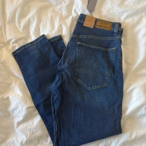 Blå loose fit jeans från Esprit - Snygga blå jeans från Esprit i loose fit-modell med klassisk femficksdesign och diskreta slitningar framtill. Jeansen har normalhög midja och raka ben. Tillverkade i mjukt bomullsjeansmaterial med en autentisk tvättad look. Perfekta för en avslappnad och trendig stil. W:32 