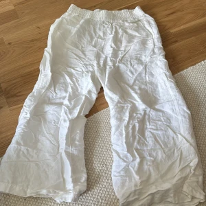 Vita linnebyxor med resårmidja - Säljer ett par luftiga vita linnebyxor med resår i midjan. Perfekta för varma dagar och har en avslappnad, loose passform. Byxorna är helvita och tillverkade i svalt linnematerial.