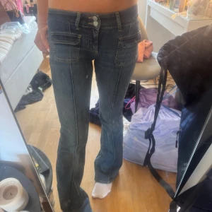Mörkblå bootcut jeans med fickdetaljer - Säljer ett par mörkblå bootcut jeans med låg midja och markerade sömmar. Använda fåtal ggr. Köpta ifrån Nelly i storlek 34. Stretchiga. 