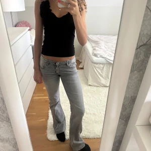 Grå bootcut jeans med knappar - Säljer ett par ljusgrå jeans med bootcut passform och snygga knappar i gylfen. Jeansen har låg midja och klassisk femficksdesign. Storlek 158 men passar någon med storlek 32 eller 34 och är tillräckligt långa för mig som är 173💕💕Använda fyra gånger.