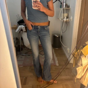 Crocker Pep! Bootcut jeans ljusblå 27/33 - Säljer ett par snygga ljusblå bootcut jeans från Crocker, modell Pep! Boot. Jeansen har klassisk femficksdesign, låg midja och lätt slitningar framtill för en cool look. Perfekta om du gillar en retro vibe och vill ha ett par jeans med lite utsvängda ben. Midjemått 34 innerbenslängd 77