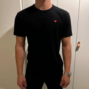 Svart CDG Tshirt - En svart snygg tshirt från märket CDG (Comme des Garçons Play) I använt skick men inga defekter. Tröjan är självklart äkta. Nypris ca 1000kr