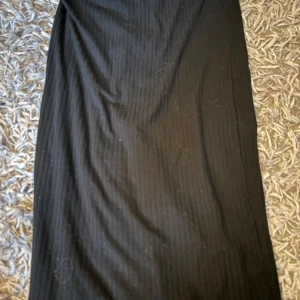 Svart långkjol från Pieces - Svart långkjol från Pieces med diskret ribbad struktur. Kjolen har en rak och enkel passform som är lätt att styla med olika toppar. Perfekt för dig som gillar en clean och stilren look.