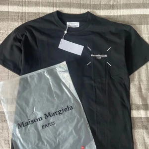 Maison Margiela svart t-shirt med tryck - Svart t-shirt från Maison Margiela med vit logga och grafiskt tryck fram och bak, helt ny! | Skick: 10 / 10 | Nypris: 2500 | Vårt pris: 799 | Storlek: M | Tveka inte att fråga om ni har funderingar! 