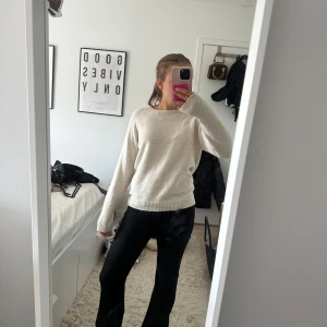 Vit stickad tröja med rund hals - Mysig vit stickad tröja med rund hals och långa ärmar. Tröjan har ribbade muddar vid ärmslut och nederkant, vilket ger en clean och enkel look. Perfekt att matcha med jeans eller kjol för en chill stil.