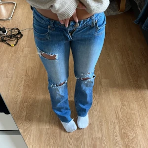 Blå bootcut jeans från Band of Industry - Säljer ett par blå bootcut jeans då de inte längre passar. Jeansen har låg midja, klassisk dragkedja och coola knappar framtill. Jag är 163 som referens och brukar ofta ha storlek xs/s i byxor. Skriv för mer info❤️