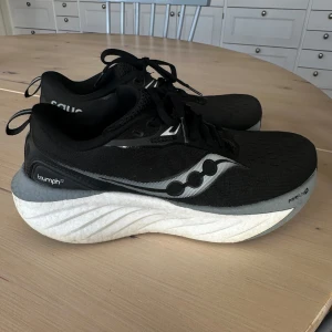 Saucony Triumph 22 löparskor - Saucony Triumph 22 sneakers i svart med grå och vit sula. Skorna har ventilerande mesh-ovandel, snörning och en pwr run sula. Använda fåtal gånger men säljer då de ej passade mitt löpsteg. Strl 38,5.