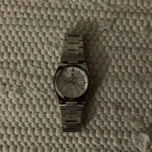 Silverfärgad klocka från Binbond - Stilren klocka från Binbond med silverfärgat armband i metall och rund urtavla. Urtavlan är vit med tydliga markeringar och datumvisning. Klassisk design som passar till många olika stilar. Quartz-urverk och robust länkarmband. Nypris 2500/ Mitt pris 2000