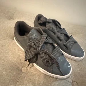 Grå sneakers med breda snören - Snygga grå sneakers från Puma med glansig finish och breda, markerade snören. Köptes för 600, säljer för 300. Bra skick🥰