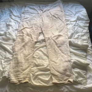Beiga linnebyxor från H&M - Säljer ett par beiga linnebyxor från H&M med avslappnad passform och raka ben. Byxorna har sidfickor och är tillverkade i ett lätt och svalt linnematerial, perfekta för varmare dagar. (Möts upp i Stockholm)