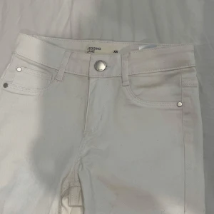 Vita skinny jeans i stretch XS - Snygga vita skinny jeans från Jegging Jane i stretchigt material. Klassisk femficksmodell med silverfärgade nitar och knapp. Perfekta för dig som gillar en tight passform och vill ha en clean look.