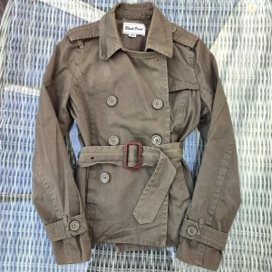 Kort kappa - Säljer en stilig kort grön kappa, perfekt till våren! Med avtagbar rem i midjan. 💫 Säljer vidare för att den inte passade. 💓 Har en fläck på flärpen nära kragen (se bild), annars i bra skick. Skriv innan ni köper, har den listad på Vinted också. 💞 Mått: Längd från axel: 53 cm Underärm: 43 cm Överärm: 57/58 cm Armhåla till armhåla: 38/39 cm Måtten kan skilja +- någon cm