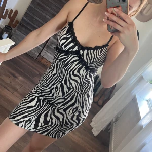 Zebramönstrad klänning - Snygg zebramönstrad klänning med smala axelband och spetsdetaljer vid bysten. 