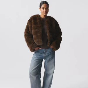 Brun pälsjacka från Gina Tricot - Säljer en snygg brun faux fur jacka från Gina Tricot. Jackan är kort och har en lyxig pälslook som passar perfekt för kyligare dagar. Den har en normal passform och är långärmad, vilket gör den både stilren och bekväm. Endast använd 1-2 gånger.