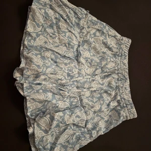 Blå mönstrade shorts kjol från Zara - Snygga blå shorts kjol från Zara med ett vitt paisleymönster. De har en elastisk midja för extra komfort och en luftig passform. Perfekta för varma dagar! Det är både shorts och en kjol❤️