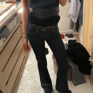 Marinblå bootcut jeans - Snygga mörkblå utsvänga jeans med vita sömmar. De har en låg midja och femficksdesign. Så coola men passar inte mig längre. Storlek xs. Midjemått rakt över: ca 35,5cm. Innerbenslängd: 76 cm. Upsprettad sömm längs ner