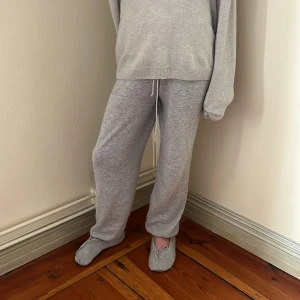 Grå kashmirbyxor - Mysiga grå mjukisbyxor med snörning i midjan. Perfekta för en avslappnad dag hemma. Byxorna har en loose passform och är tillverkade i ett mjukt material som ger extra komfort.