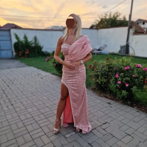 Balklänning/galaklänning  - Säljer en glamorös rosa långklänning med paljetter och en elegant slits. Klänningen är one shoulder och har en vacker snörning i ryggen. Perfekt för en festlig kväll!