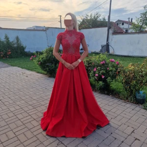 Balklänning/galaklänning  - Fantastisk röd långklänning med vackra spetsdetaljer och hög hals. Klänningen har några deffekter där pärlorna inte sitter fast ordentligt men inget som syns från avstånd. Perfekt för en glamorös kväll.