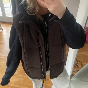 Brun Zara väst - Säljer en brun dunväst med dragkedja från Zara i storlek S. Helt oanvänd så perfekt skick. Perfekt till våren! 