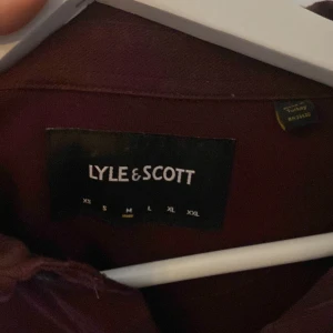 Vinröd pikétröja från Lyle & Scott - Säljer en stilren vinröd pikétröja från Lyle & Scott.
