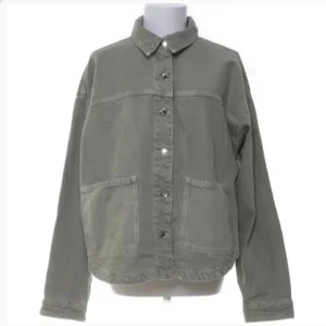 Grön jeansjacka - Snygg grön jeansjacka med knappar framtill och två stora fickor. Perfekt för en avslappnad stil. Jackan har en klassisk krage och långa ärmar. Köptes sommaren 2024 å e knappast använd ser helt ny ut💕 bilden är lånad men de är samma jacka