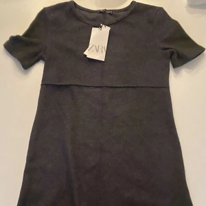 Svart klänning från Zara - Snygg svart klänning från Zara med korta ärmar och en stilren design. Perfekt för en chic och enkel look. Tillverkad i ett mjukt material som ger en bekväm passform.