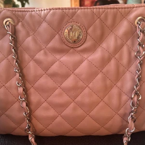 Söt axelväska från Don Donna! - Söt ljusrosa quiltad axelväska med flera fack och dragkedja i fuskskinn från Don Donna. Mått: 30 x 25 cm. Superfint skick!