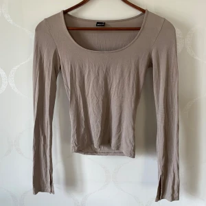 Beige långärmad topp från Gina Tricot - Säljer en stilren beige långärmad topp från Gina Tricot. Toppen har en rundad halsringning och är tillverkad i ett mjukt material som ger en skön passform. Perfekt för en enkel och snygg look. Hör av dig vid intresse! 😊