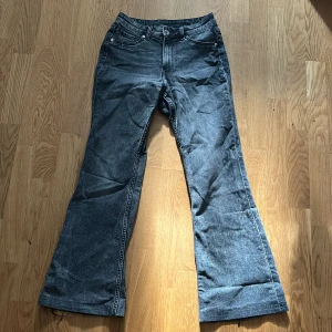 Grå jeansbyxor från H&M - Snygga grå jeansbyxor från H&M med bootcut-stil. Byxorna har en klassisk femficksdesign och är tillverkade i en bomullsblandning för extra komfort. Perfekta för en avslappnad look. Innebenslängden är 71 cm. Midjemått 33 cm.