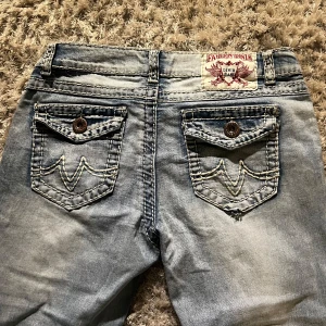Vintage lowrise jeans - Snygga lågmidjade  ljusblå jeans med unika broderade fickor och knappar. De har en klassisk femficksdesign och en bekväm passform. Priset går att pruta. Midjemått ca 38cm och Innerbenslängden ca 77-78cm. Se sista bild.