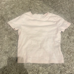 Ljusrosa t-shirt - Säljer en enkel och stilren ljusrosa t-shirt. Den har en normal passform och är kortärmad, perfekt för en avslappnad look. Tillverkad i ett mjukt material som känns skönt mot huden.