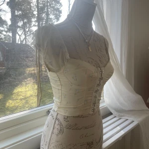 Vit korsettopp från Princess Polly - Säljer en söt vit korsettopp från Princess Polly med korta puffärmar och snörning framtill. Toppen är croppad och har en romantisk stil med fina detaljer. Perfekt för en trendig look! Köpte på Sellpy för ett år sedan och varan är i bra skick. Använd aldrig pga att jag har blivit tjockare.