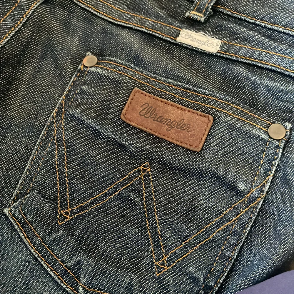 Mörkblåa jeans från Wrangler i nyskick med bra kvalitets denim, sitter lågmidjade och bootcut i strl W28 ~ S/36 // midja tvärsöver 38cm, innerbenslängd 79cm, ytterbenslängd 97cm, grenhöjd 18. Farkut & Housut.